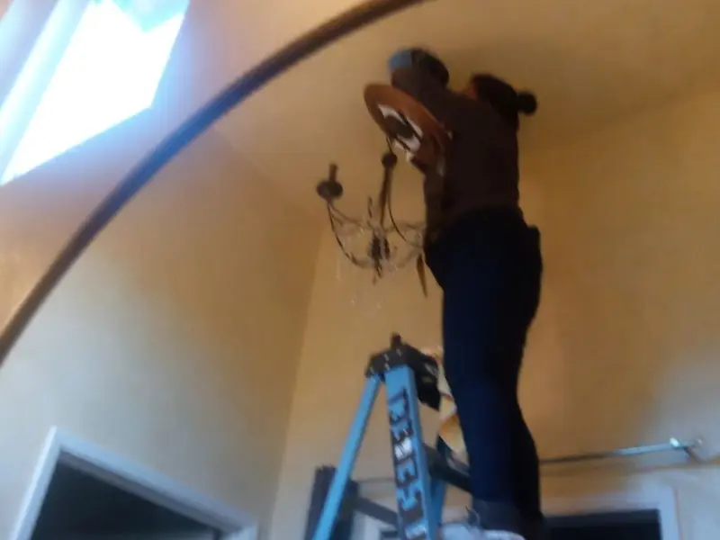 Electrician installing a chandelier in a Cambridge residence